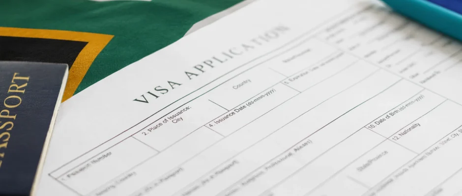 Passport and visa application form on top of a South African flag representing South Africa work visa requirements
