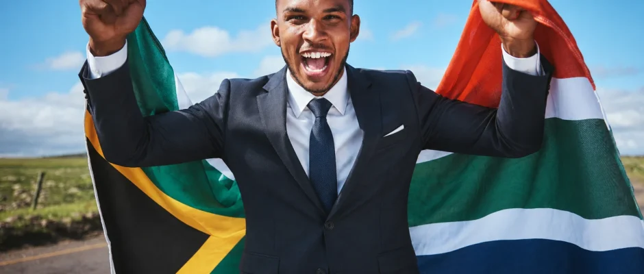 Man in a business suit holding the South African flag while celebrating South African citizenship by naturalisation