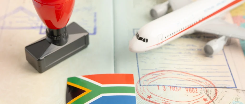 How to get a South African tourist visa with passport, South African flag, visa stamp and airplane